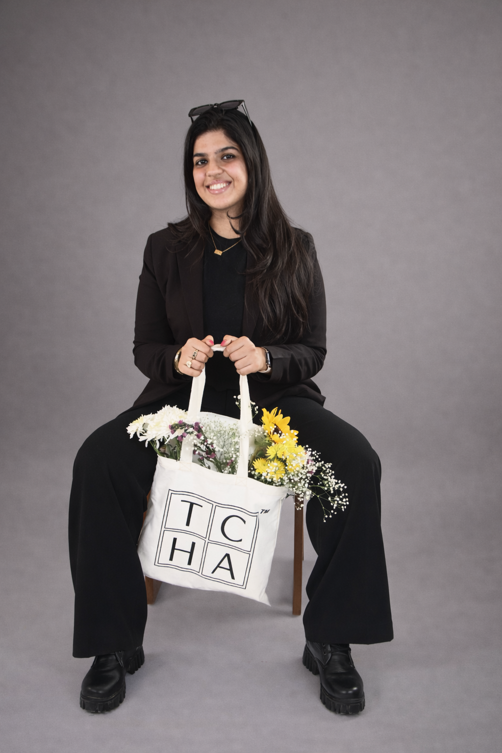 Woman holding a tote bag with flowers against a gray background